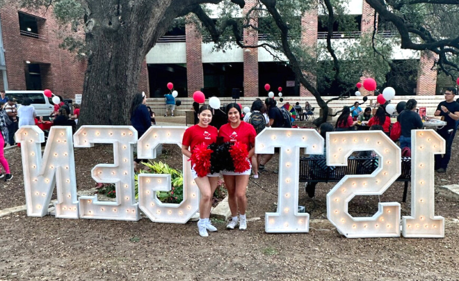 Two first-gen students standing between 1st gen signs